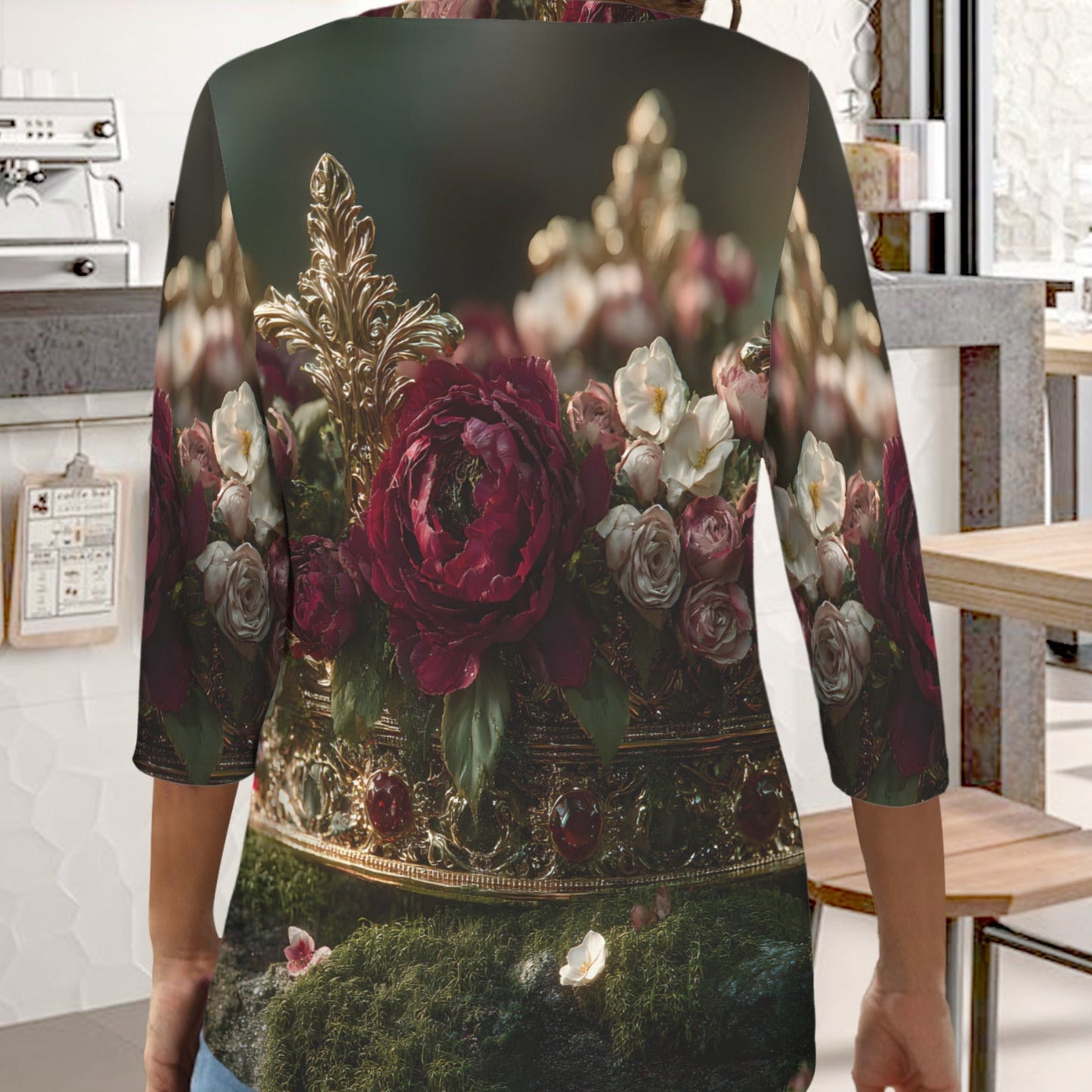 A woman wearing a three-quarter sleeve top with a detailed vintage-style floral print, shown from behind in a cafe setting.