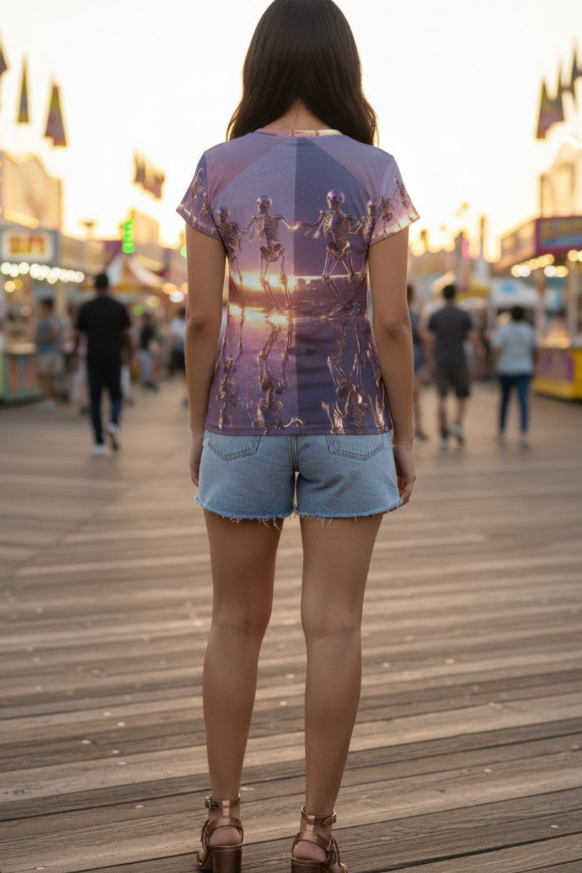 Person wearing a graphic t-shirt on a boardwalk with fairground lights in the background