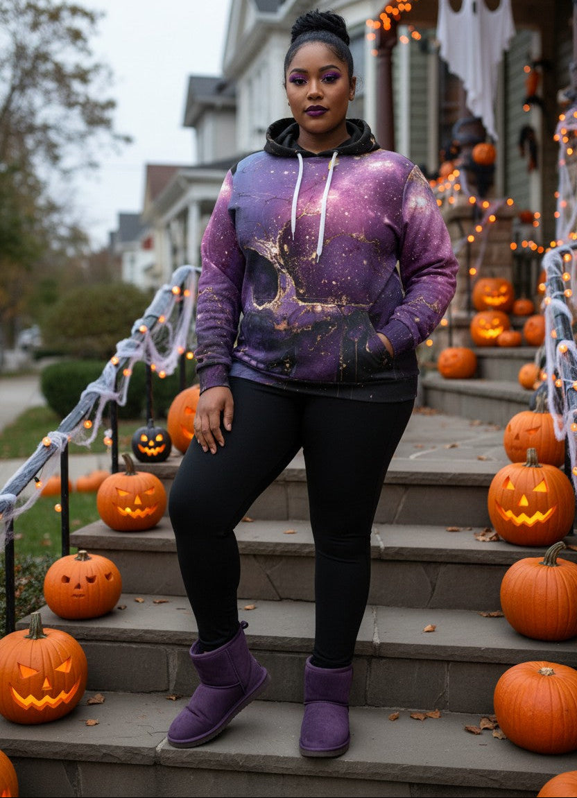 A woman stands on front steps decorated with jack-o'-lanterns and Halloween lights, wearing a purple galaxy-print hoodie, black leggings, and purple UGG boots.