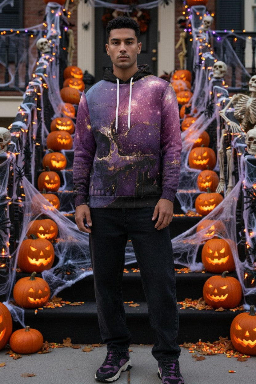 A man stands on a Halloween-decorated front staircase wearing a purple galaxy-print hoodie, black pants, and purple sneakers. The scene includes pumpkins, skeletons, cobwebs, and string lights.