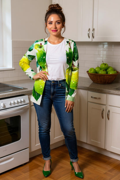 Woman in a kitchen wearing a colorful apple cardigan, white shirt, and blue jeans.
