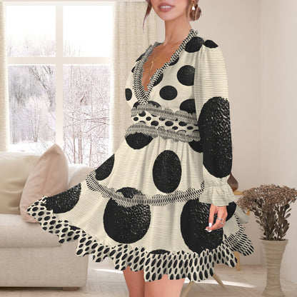 A woman wearing a long-sleeve V-neck dress with a black and off-white polka dot pattern, standing in a bright living room.