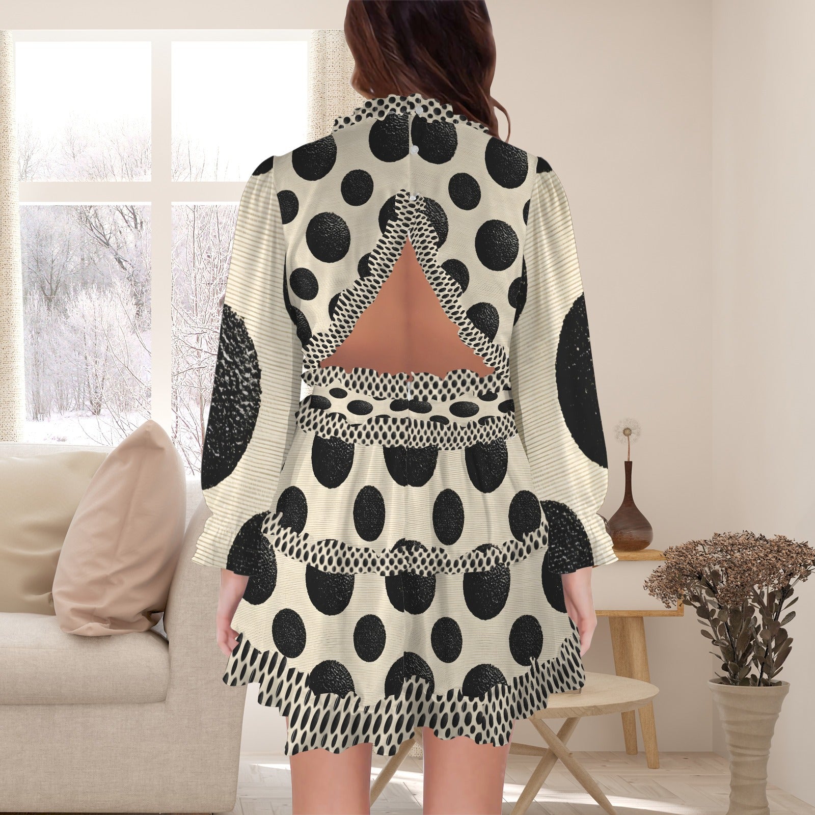 A woman stands with her back to the camera wearing a short cream dress with large black polka dots, textured black circular patches, and a triangular open back detail.