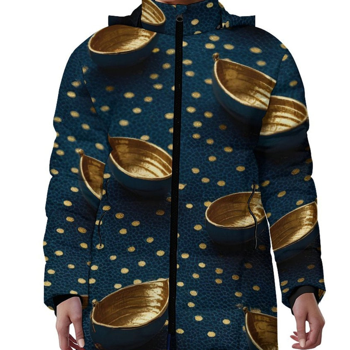 A woman wearing a hooded zip-up jacket with a dark teal pattern featuring gold bowls and gold dots, paired with blue jeans against a plain white background.