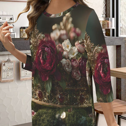 A woman wearing a three-quarter sleeve tunic top with a vintage-style floral print featuring large burgundy and pink roses, white flowers, and a dark green background, set in a cafe environment.