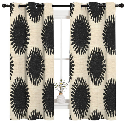 A pair of grommet-top window curtains with a bold black and cream abstract sunburst pattern, hanging on a black rod over a white window frame.