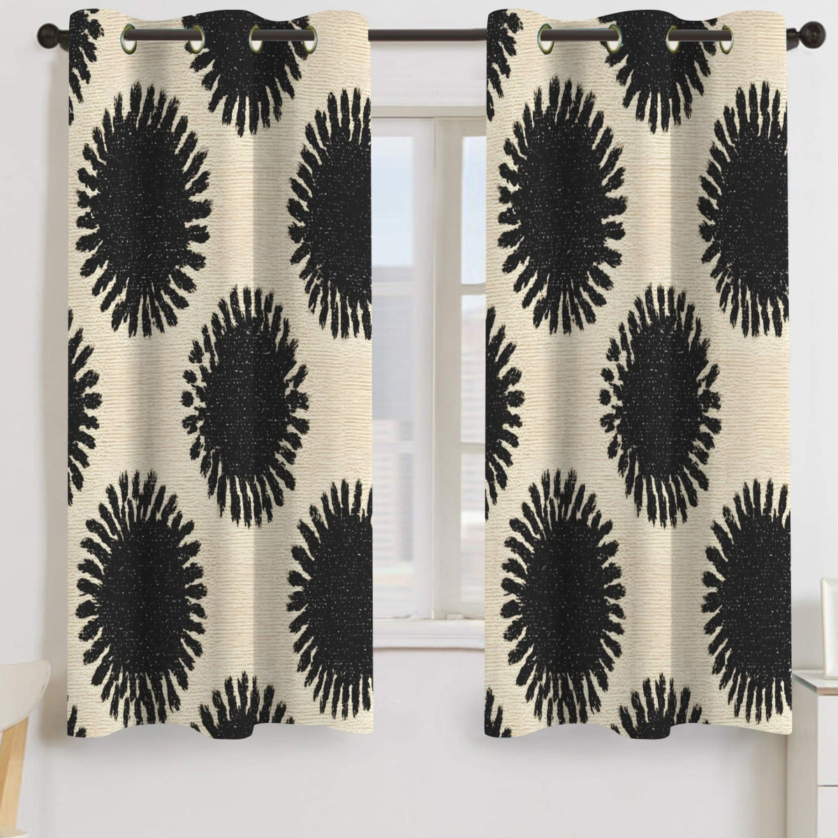 A pair of grommet-top curtain panels hanging on a dark rod in front of a window. The curtains have a textured cream background with a bold black radial sunburst pattern.