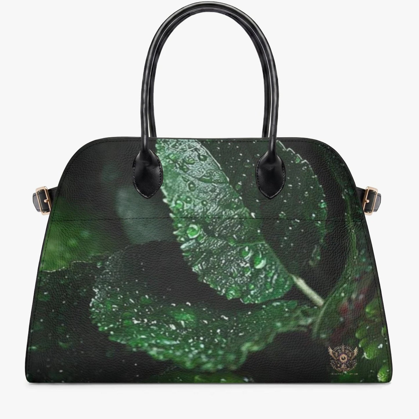 A structured black handbag with a glossy finish, featuring a printed design of green leaves covered in water droplets on the front panel. It has two black top handles and small gold-tone side hardware, shown against a plain light gray background.