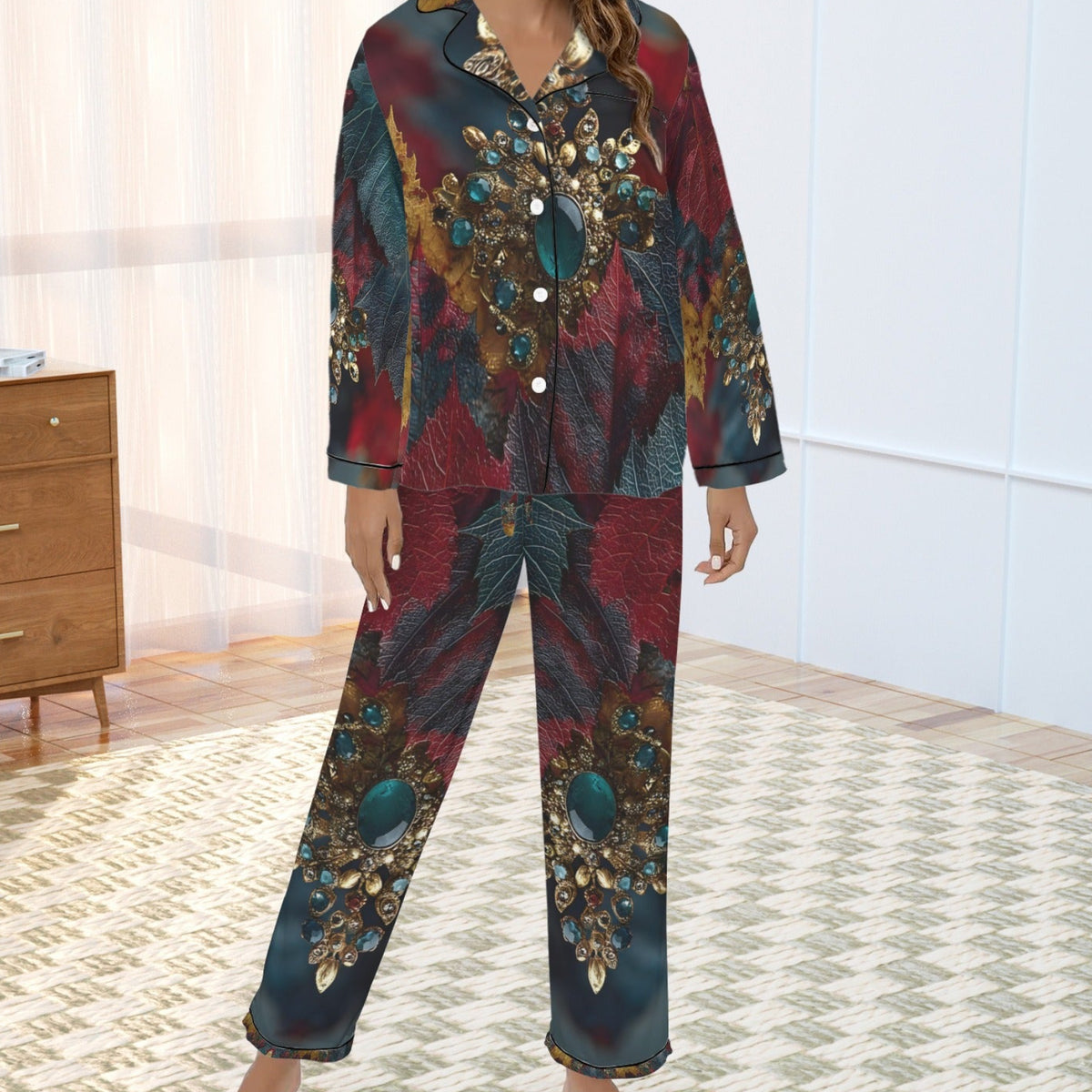 A woman modeling a two-piece pajama set with a dark teal, red, and gold abstract floral pattern, standing in a brightly lit bedroom.