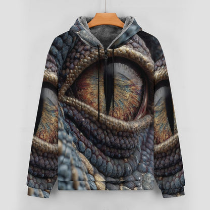 A hooded sweatshirt hanging on a wooden hanger against a light gray wall. The hoodie features an all-over printed design of a reptile or dragon eye with detailed scales and warm brown, gold, blue, and gray tones.