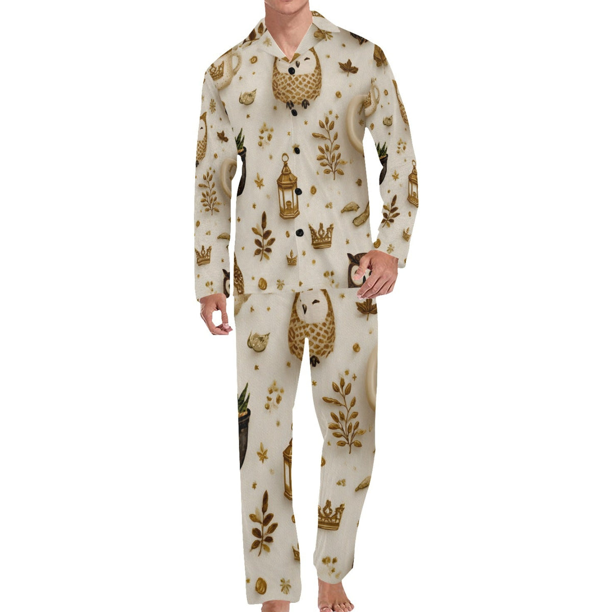 A man modeling a two-piece long-sleeve pajama set with an owl-themed print. The pajamas are cream-colored with brown and gold owl, leaf, lantern, and crown motifs.