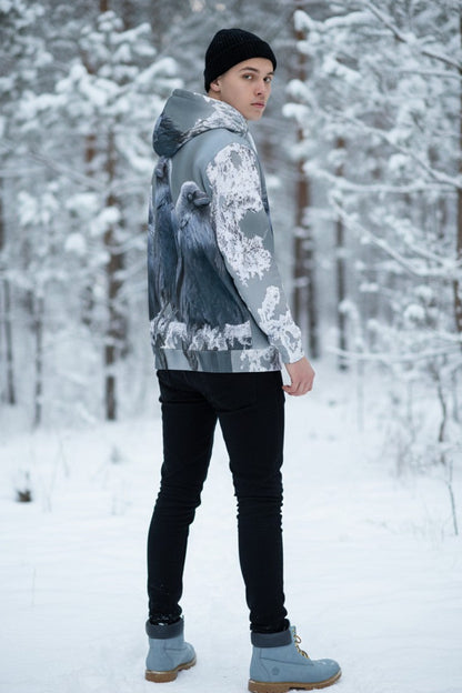 A person standing in a snowy forest wearing a gray and white patterned hooded jacket, black pants, a black beanie, and light blue boots.