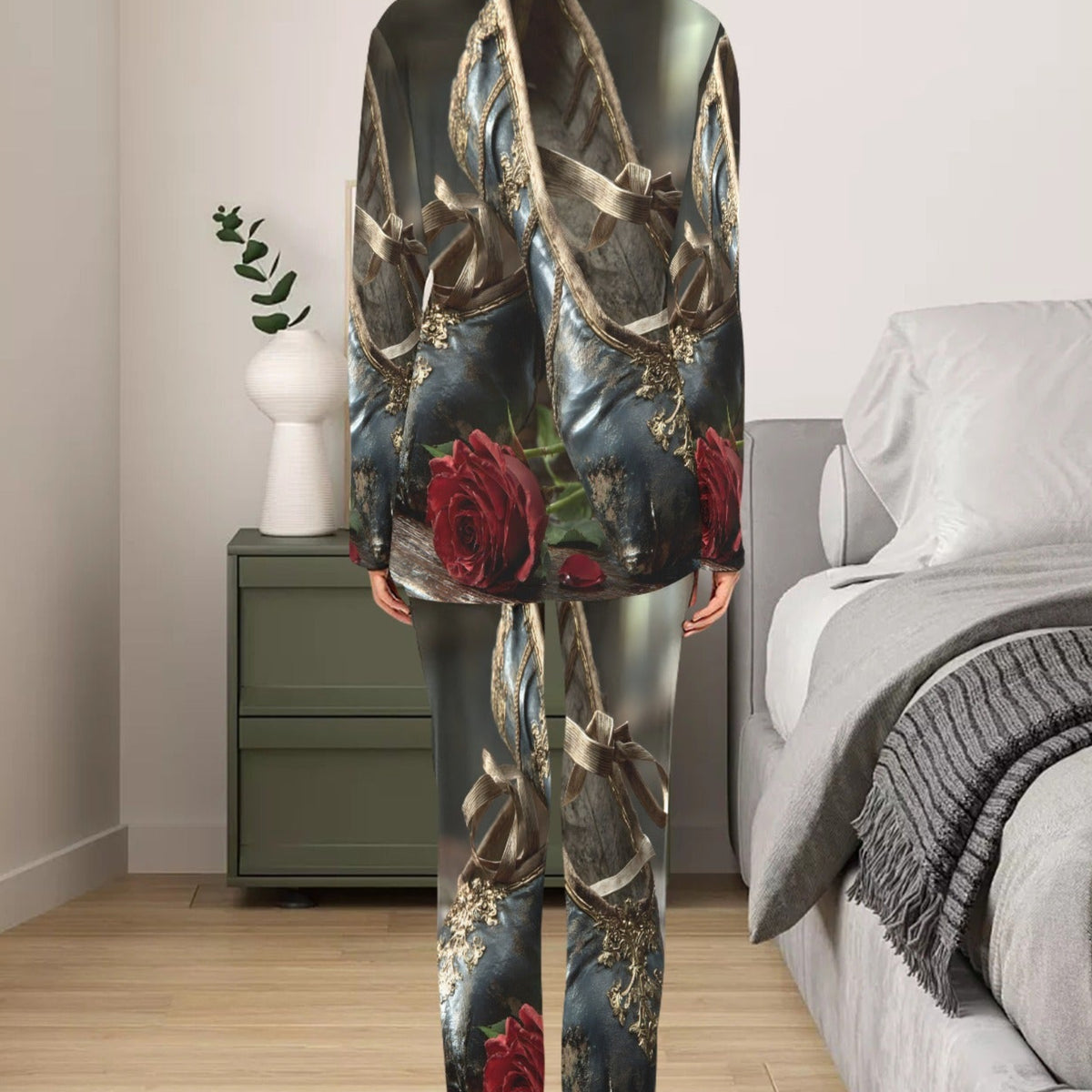 A woman stands with her back to the camera in a bedroom, wearing a matching pajama set with a dark, metallic, and floral print featuring red roses and gold ribbon motifs.