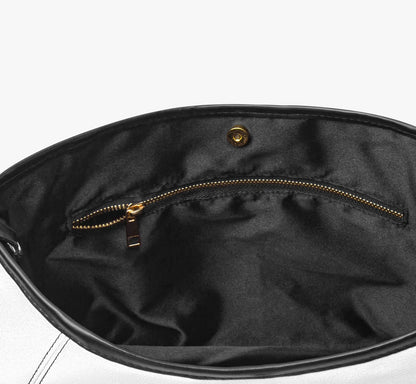 Close-up of the interior of a black handbag, showing a black fabric lining with a gold zipper pocket and a gold snap button closure.