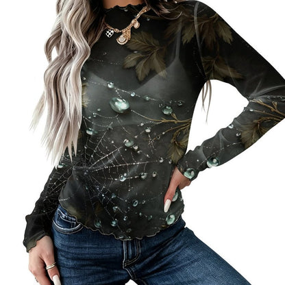 A woman wearing a long-sleeve black top with a spiderweb and dewdrop print, paired with blue jeans, shown against a plain white background.