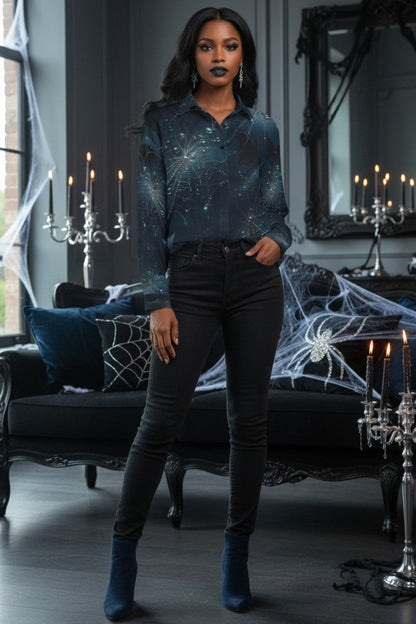 A woman stands in a dark, gothic room wearing a long-sleeve button-up shirt with a dark blue and black celestial pattern, paired with black skinny jeans and dark blue ankle boots.