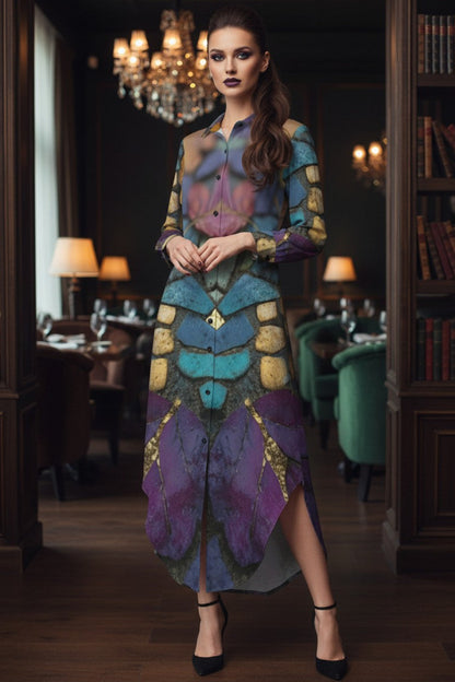 A woman stands in a dimly lit, elegant interior with bookshelves and chandeliers, wearing a long-sleeve button-front dress with an abstract, painterly pattern in purple, teal, blue, and gold.