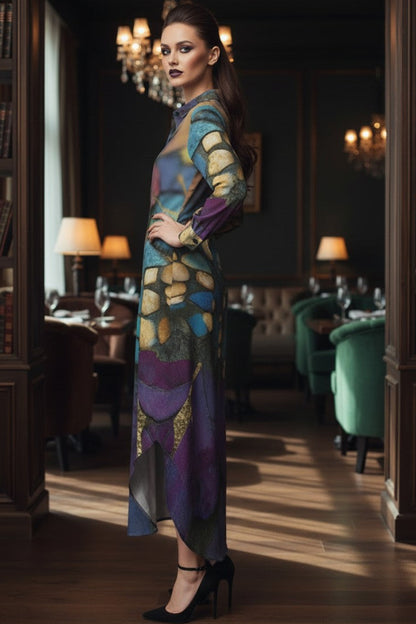 A woman stands in a dimly lit, elegant library or study wearing a long-sleeved, high-neck maxi dress with a colorful abstract pattern in purple, blue, green, and gold. She is wearing black high heels and posing with one hand on her hip.