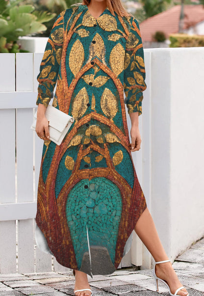 A woman wearing a long-sleeve maxi dress with a detailed botanical pattern in teal, gold, and brown, holding a white clutch and standing outdoors next to a white fence.