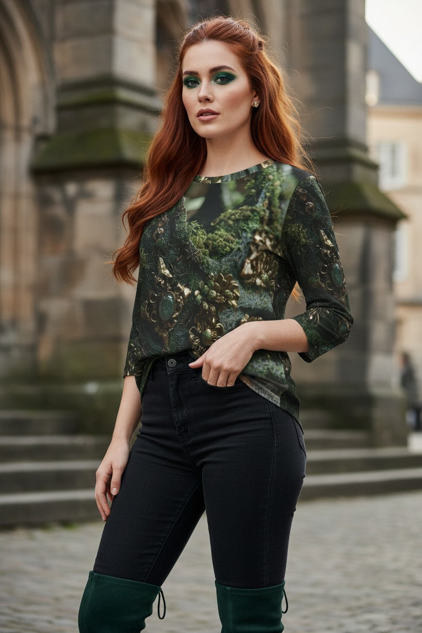 A woman with red hair stands outdoors in front of a stone building, wearing a dark green and black patterned long-sleeve top, black pants, and dark green knee-high boots.