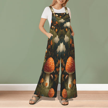 A woman modeling a pair of wide-leg jumpsuit overalls with a detailed forest and mushroom print, worn over a white t-shirt. The jumpsuit features a dark forest background with large orange and white mushrooms, green foliage, and beige clouds.