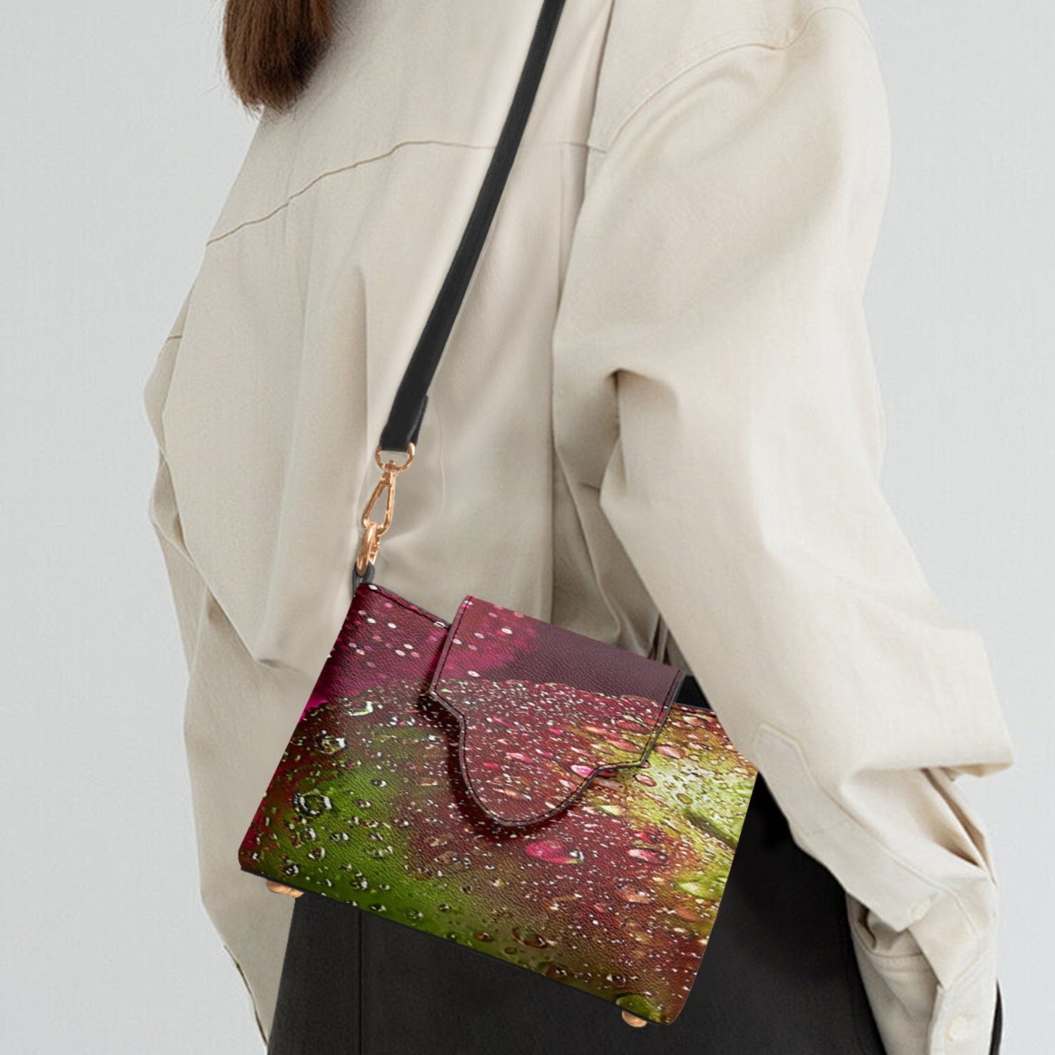 A woman wearing a cream-colored jacket and dark trousers is shown from a side-back angle, carrying a small shoulder bag with a colorful, textured glittery pattern in pink, green, and gold.