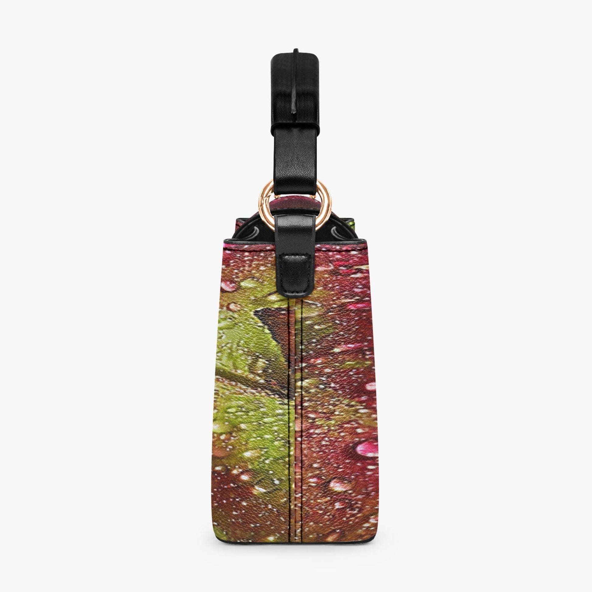 A rectangular luggage tag with a colorful abstract print featuring green, pink, and brown tones, complete with a black strap and gold-tone hardware, shown against a plain light gray background.