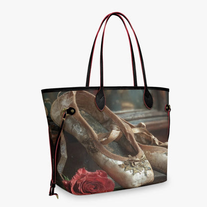 A tote bag featuring a vintage-style print of ballet slippers and a red rose, with dark red handles and trim, shown against a light gray background.