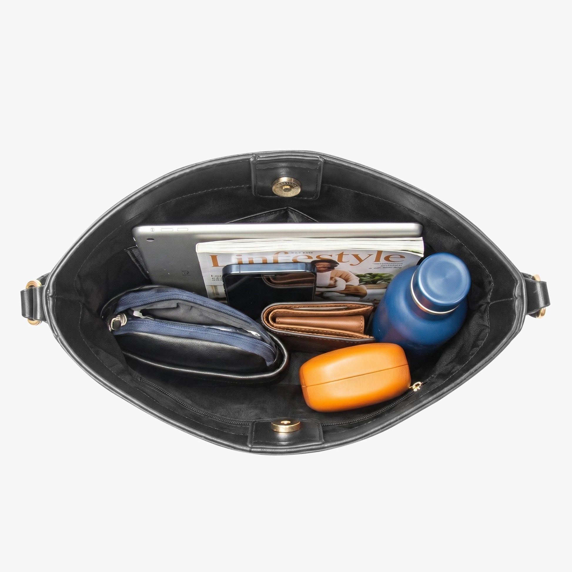 Black handbag with various items including a magazine, water bottle, and wallet on a white background