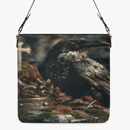 A shoulder bag with a printed design of a raven perched next to an ornate crown, shown against a plain light gray background.
