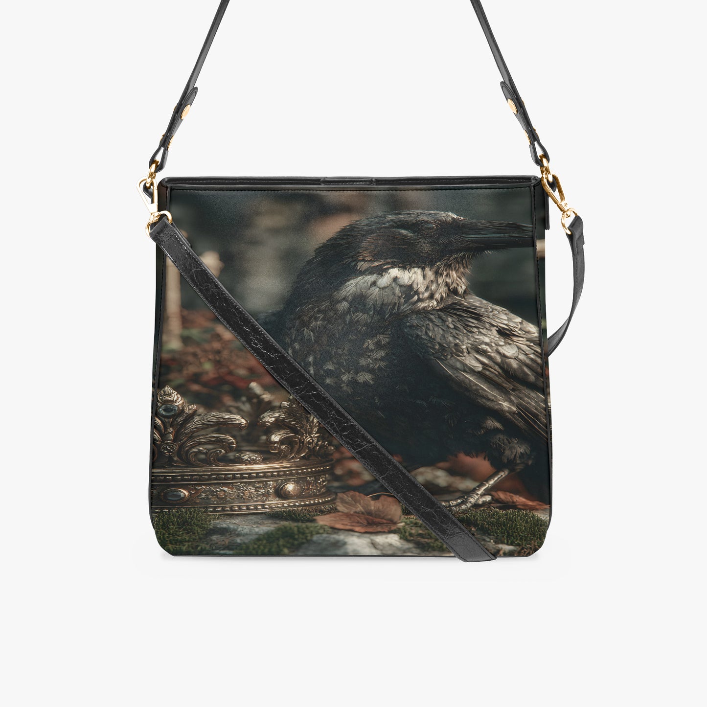 A square black shoulder bag featuring a detailed print of a raven perched on a decorative gold crown, with a black leather strap and gold-tone hardware, shown against a plain white background.