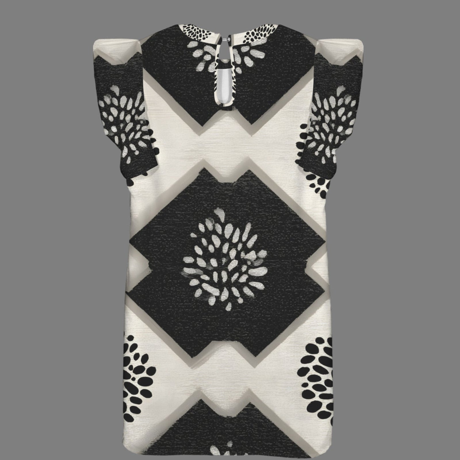 A sleeveless baby dress with a black and off-white geometric pattern featuring diamond and chevron shapes, displayed on a solid gray background.