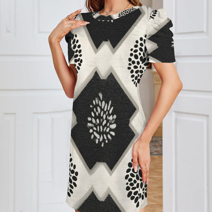 A woman wearing a short-sleeve geometric print dress with black, white, and gray patterns, standing in front of a white paneled door.
