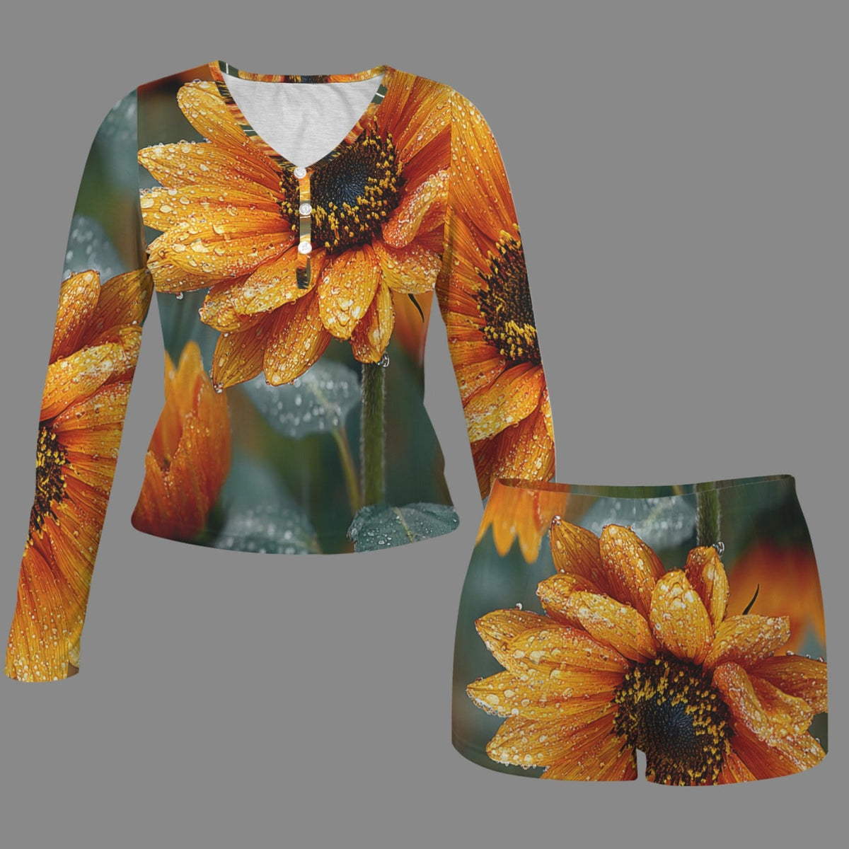 A matching two-piece clothing set featuring a long-sleeve henley shirt and shorts, both printed with a vibrant orange sunflower and green foliage pattern with water droplets, shown on a solid gray background.