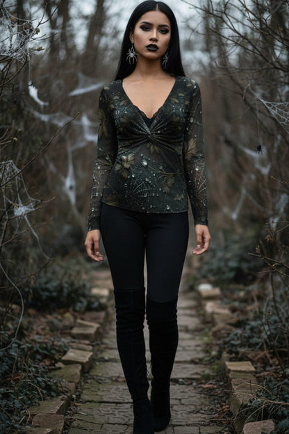 A woman stands on a stone path in a wooded outdoor setting wearing a dark long-sleeve V-neck top with a twisted front detail and black leggings.