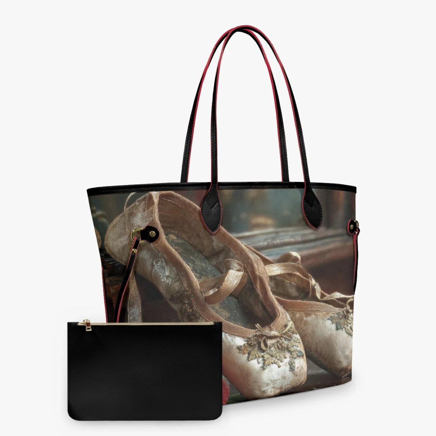 A tote bag with a printed image of ballet slippers, featuring black leather handles and trim, shown alongside a matching black zip pouch on a light gray background.