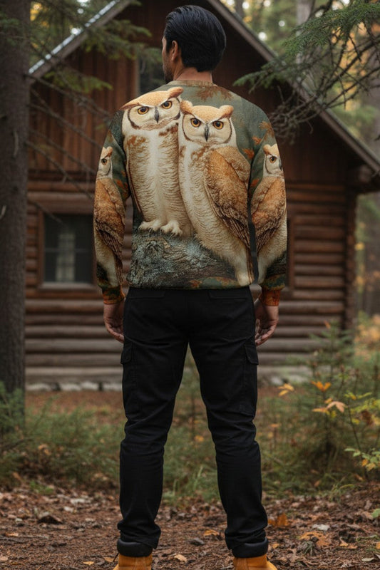 A man viewed from behind wearing a long-sleeve crewneck shirt with a realistic owl print, standing in a forest in front of a rustic log cabin.
