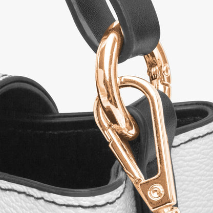 Close-up of a white handbag with a gold clasp on a light gray background