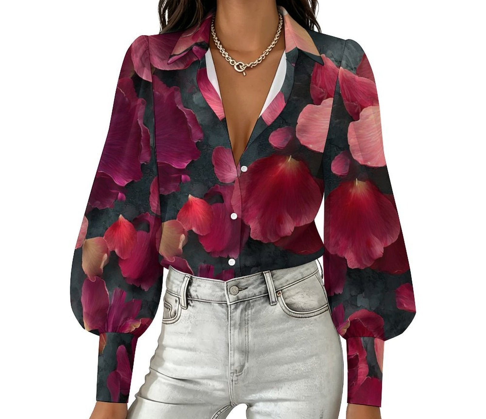 A woman wearing a long-sleeve button-up blouse with a bold floral print in deep pink, burgundy, and dark green, paired with light-wash jeans and a gold chain necklace, shown against a plain white background.