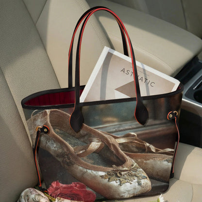 A tote bag with a vintage ballet shoe print sits on a beige car seat, styled with a magazine and flowers.